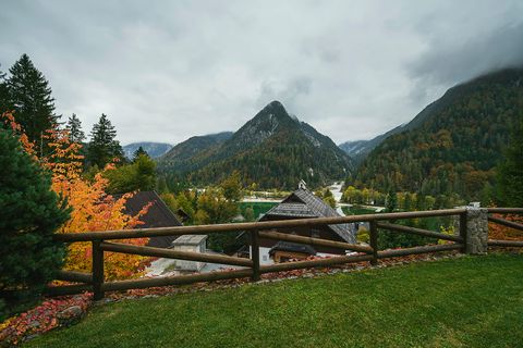 The view from the lawn across a timber fence and autumn trees to the valley and a sharp mountain peak beyond.